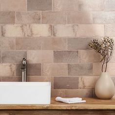 a white sink sitting on top of a wooden counter next to a vase filled with flowers