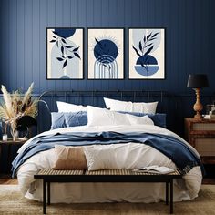 a bedroom with blue walls and white bedding, two paintings on the wall above the bed