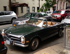 there is a green convertible car parked on the side of the street