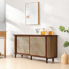 a white room with a wooden cabinet and plants on the sideboard next to it