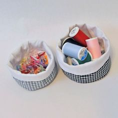 two baskets filled with different types of crafting supplies on top of a white table