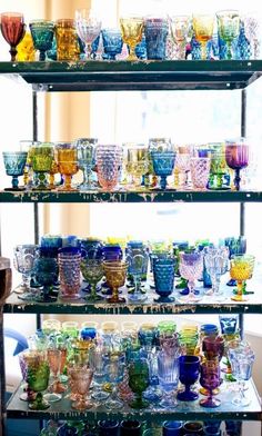 several shelves filled with different colored glass cups