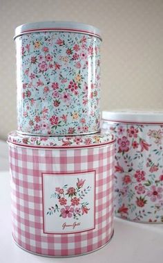 three tins with flowers and gingham designs on them are stacked next to each other