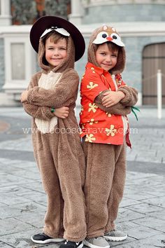 two young children dressed in animal costumes standing next to each other on the sidewalk with their arms crossed