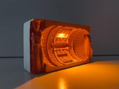 an orange light that is on top of a white box with a statue in it