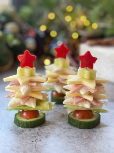 small sandwiches are arranged in the shape of christmas trees on cucumbers and tomato slices