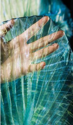 a person's hand wrapped in plastic with their fingers on the palm tree leaf