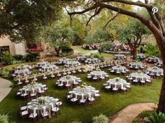 tables and chairs are set up in the middle of an outdoor garden area for a wedding reception