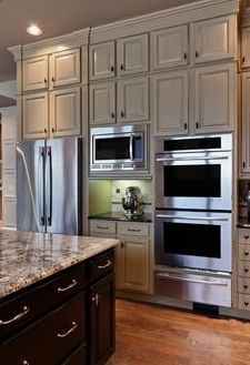 a kitchen with white cabinets and stainless steel appliances in the center, along with hardwood floors