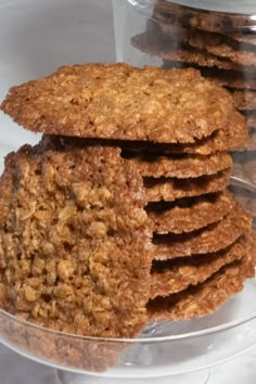 several cookies stacked on top of each other in a glass bowl next to an empty container