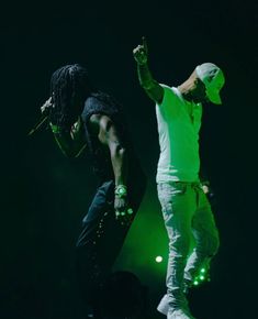 two men standing on stage with one holding his hand up