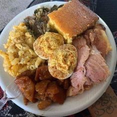 a white plate topped with meat, eggs and other foods on top of a table