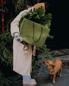 a woman carrying a green shopping bag next to a brown dog