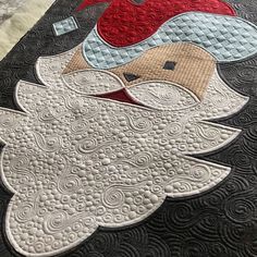 a close up of a quilted santa clause on a black table cloth with white and red accents