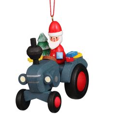 a christmas ornament with a santa clause riding a toy tractor