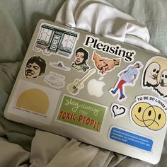 an apple laptop covered in stickers on a bed