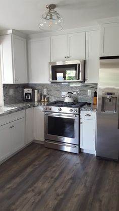 a kitchen with white cabinets and stainless steel appliances