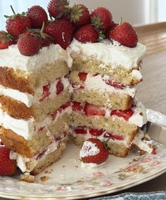 a piece of cake with strawberries on top is cut in half and sits on a plate