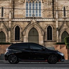 a black car parked in front of a large building