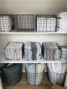 the shelves are organized with baskets and blankets for storage in this closet, which is also filled with folded linens