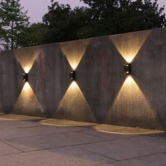 three lights are lit up on the side of a concrete wall that is lined with cement blocks