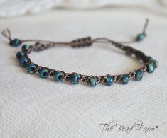 a close up of a bracelet on a white cloth with blue beads and silver wire