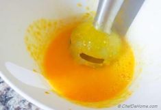 a yellow smiley face in a white bowl with two tongs sticking out of it