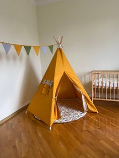 a teepee tent sitting on top of a wooden floor next to a crib