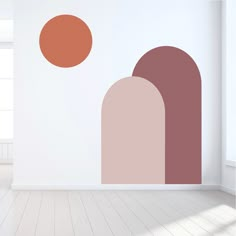 an empty room with white walls and two orange circles on the wall, one in front of the other