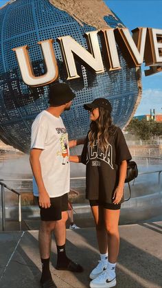 two people standing next to each other in front of a large sign that says universal