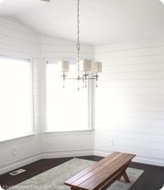 a wooden bench sitting in the middle of a living room next to a large window