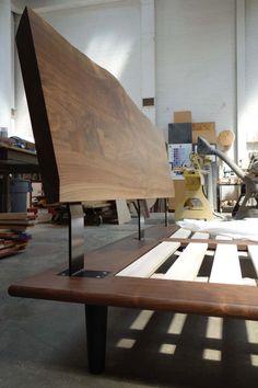 a wooden bench sitting inside of a building next to other woodworking tools and materials