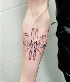 a person with a tattoo on their arm holding skis