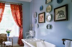 a bath tub sitting next to a window in a room with pictures on the wall