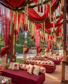 red and gold wedding decor with flowers on the ceiling, couches in front of them