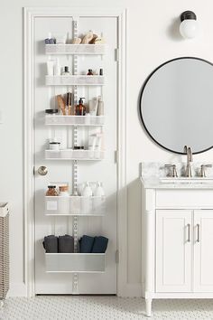 a white bathroom with shelving and a round mirror on the wall next to it