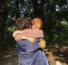 two people hugging each other in the park