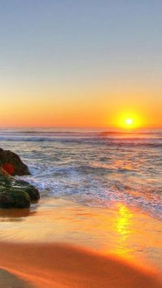 the sun is setting over the ocean on the beach