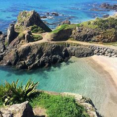 the beach is surrounded by rocks and blue water