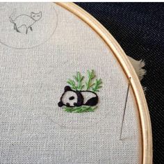 a panda bear sitting on top of a green leafy tree next to a wooden hoop