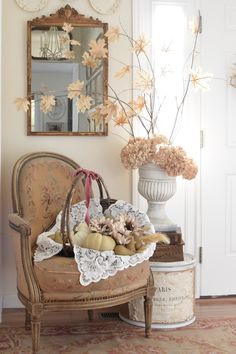 a room with a chair, mirror and vase filled with flowers on top of it