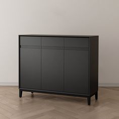 a black cabinet sitting on top of a hard wood floor next to a white wall