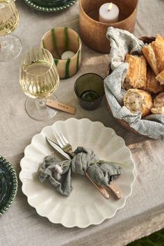 a table topped with plates and bowls filled with food next to glasses of wine on top of a table