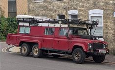 a red land rover vehicle parked in front of a brick building