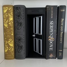 three books are lined up on a shelf next to each other, and one is open