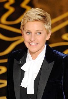 a woman in a tuxedo smiles at the camera