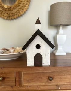 a white birdhouse sitting on top of a wooden dresser