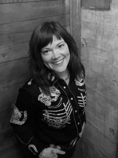 a black and white photo of a woman in a skeleton shirt smiling at the camera