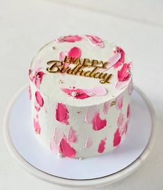 a white and pink birthday cake on a plate