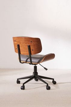 an office chair with black leather seat and wheels on a white floor in front of a wall